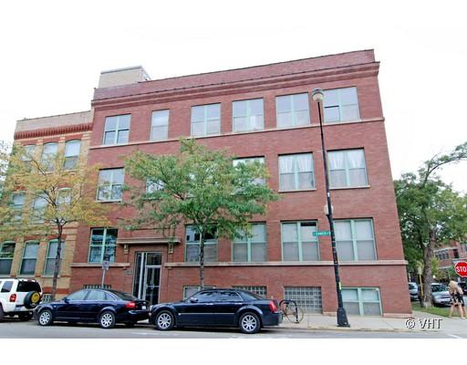 Front view of a multi-story brick building with several windows and parked cars.