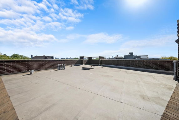 Flat rooftop with brick walls and utility pipes.