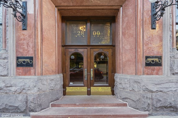 Entrance of a building with decorative wooden doors and stone facade.