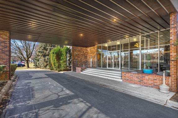 Front view of a building entrance with glass doors and a covered walkway.