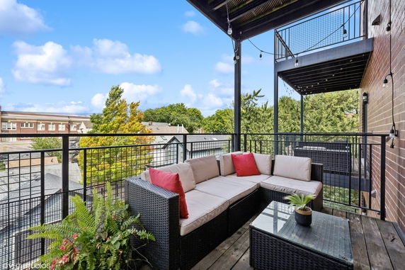 Outdoor patio area with seating and view of rooftops and trees.
