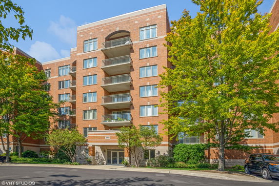 Front view of a multi-story brick apartment building with balconies.