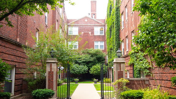 Front view of a brick apartment building with greenery.