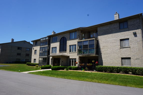 Front view of a multi-story residential building with balconies and brick exterior.