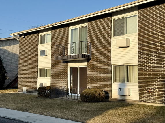 Front view of a two-story brick apartment building with balconies and windows.