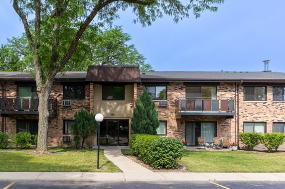 Front view of a two-story brick apartment building with balconies and a central entrance.