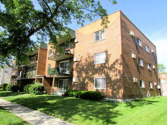 Front view of a multi-story brick apartment building with balconies.