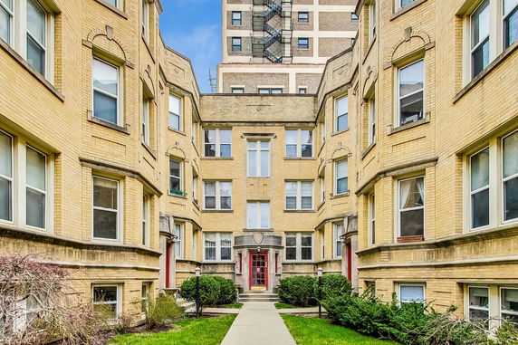 Front view of a multi-story brick apartment building with symmetrical design and multiple windows.