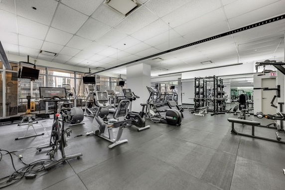 Interior view of a gym with various exercise equipment, including treadmills and weight machines.
