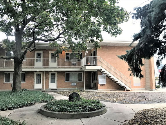 Front view of a two-story brick building with external staircases and balconies.