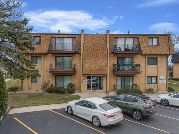 Front view of a three-story apartment building with parking in front.