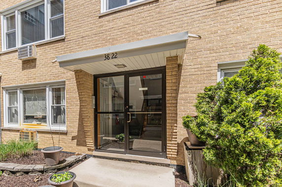 Front view of a brick building entrance with glass door and awning.