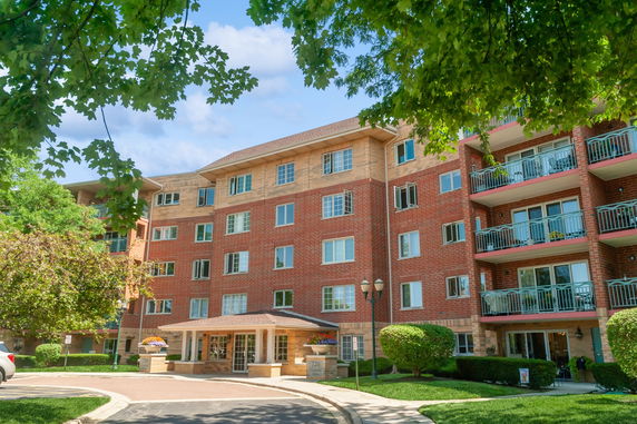 Front view of a multi-story residential building with balconies and a central entrance.