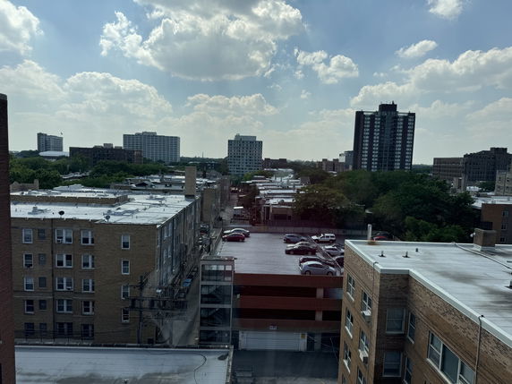 Cityscape view with mid-rise buildings and a parking area.