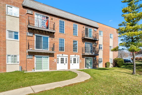 Front view of a three-story brick apartment building with balconies.