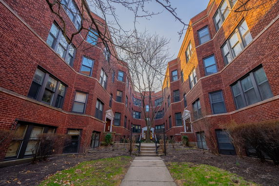 Front view of a multi-story brick apartment building with multiple entrances.