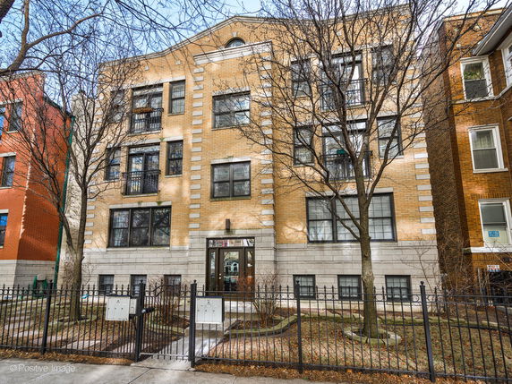 Front view of a multi-story brick building with a gated entrance.