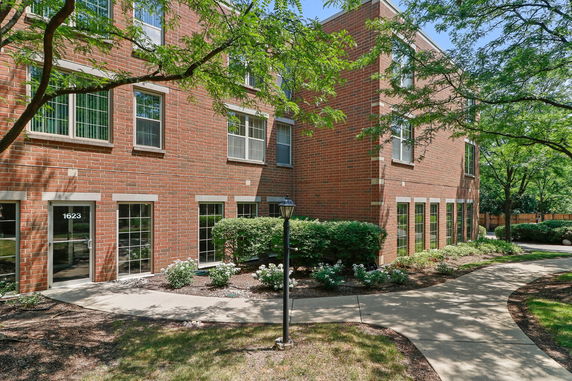 Front view of a brick apartment building with multiple windows and a walkway.