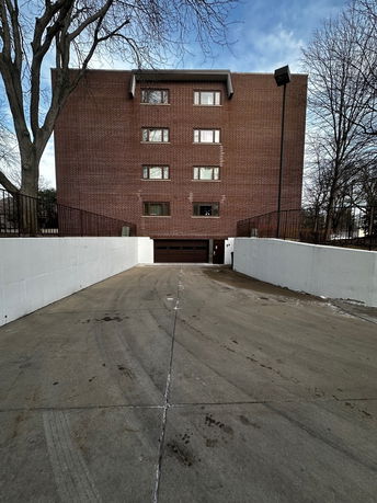 Front view of a multi-story brick building with driveway leading to a garage.