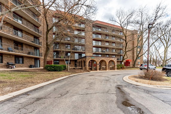 Front view of a multi-story brick apartment building with balconies.