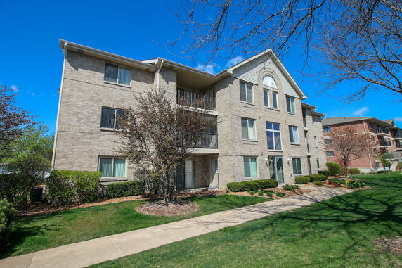 Front view of a three-story residential building with a brick exterior and multiple windows.