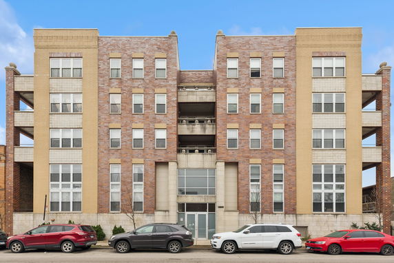 Front view of a multi-story brick apartment building with large windows.