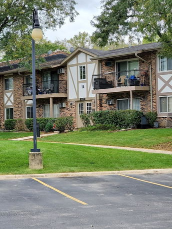 Front view of a multi-story residential building with balconies and brick facade.