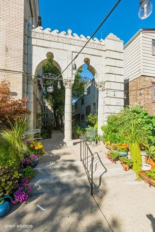 Front view of a building with an ornate stone archway entrance and a garden path.