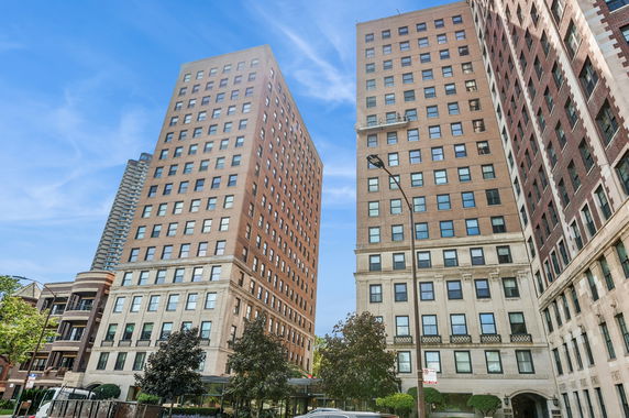 Front view of two tall residential buildings with multiple windows against a blue sky.