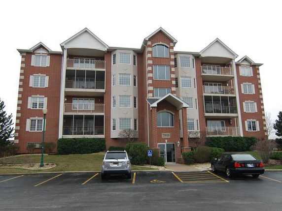 Front view of a multi-story apartment building with a parking area.