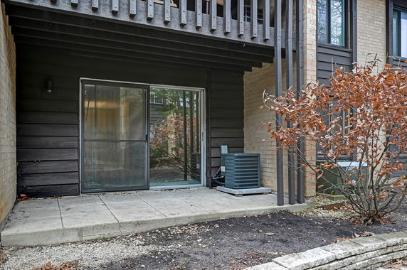 Front view of a house with sliding glass door and an air conditioning unit on a concrete patio.