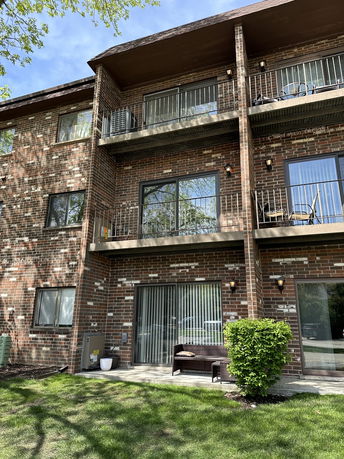 Front view of a multi-story brick apartment building with balconies.
