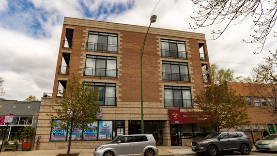 Front view of a four-story brick building with balconies and large windows.