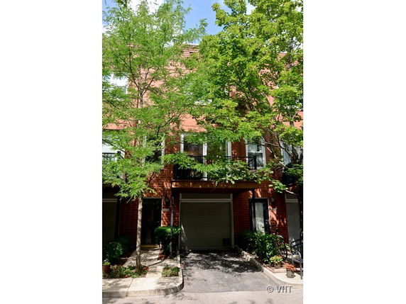 Front view of a multi-story residential building with garage and trees.