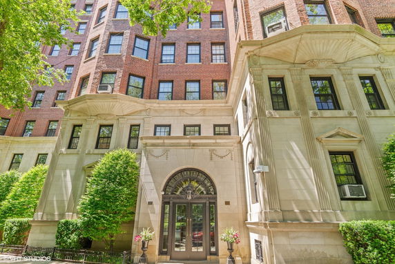 Front view of a multi-story brick apartment building with detailed stonework around the entrance.