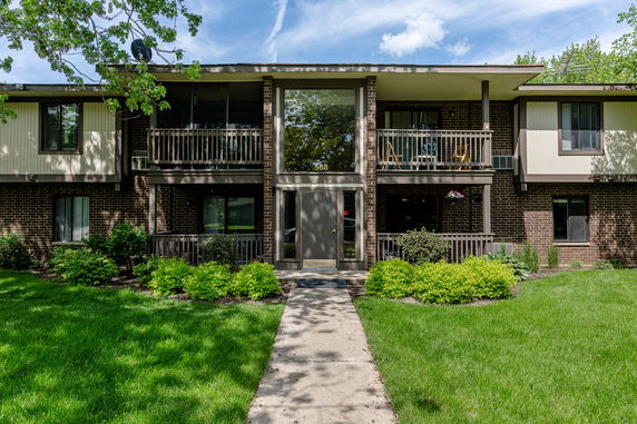 Front view of a two-story apartment building with a central entrance and balconies.