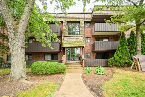 Front view of a multi-story brick building with balconies and a central entrance.