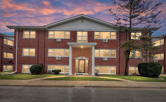 Front view of a multi-story brick building with columned entrance.