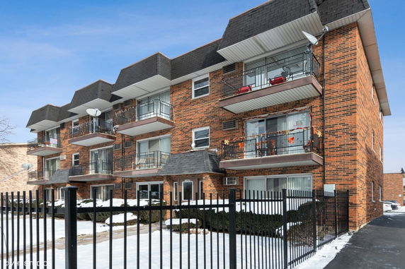 Front view of a multi-story brick apartment building with balconies.