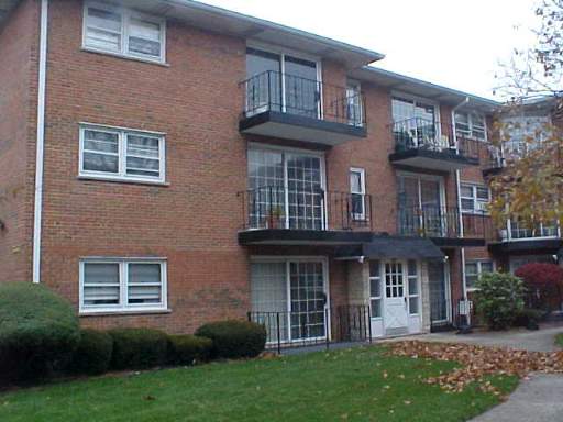 Front view of a three-story brick apartment building with balconies.