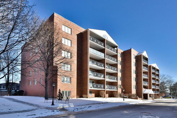 Front view of a multi-story brick apartment building with balconies.