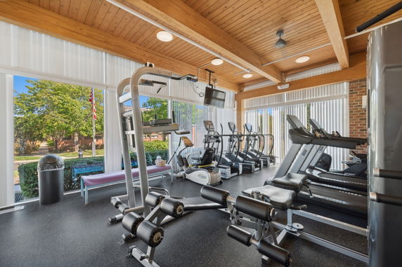 Interior view of a gym with exercise equipment and large windows.