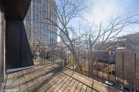 Balcony view of urban surroundings with tall buildings and trees.