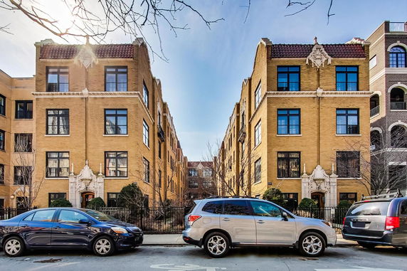 Front view of two adjacent apartment buildings with ornate architectural details and large windows.