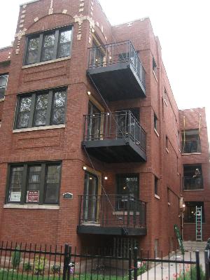 Front view of a multi-story brick building with balconies and large windows.
