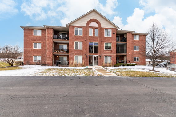 Front view of a three-story brick residential building with balconies.