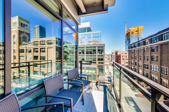 View from a balcony showing a cityscape with modern buildings and clear blue sky.