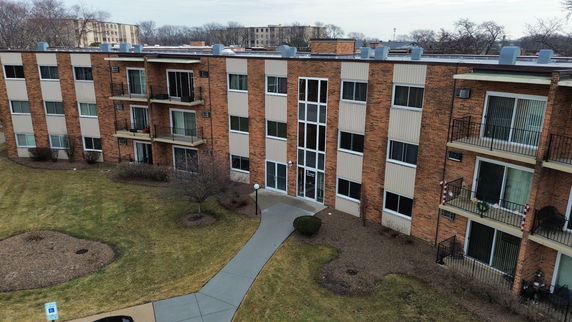Front view of a multi-story brick apartment building with balconies.