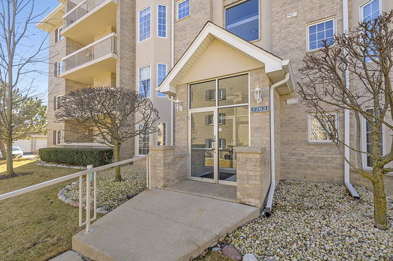 Front view of a multi-story building with a glass entry door and balconies.