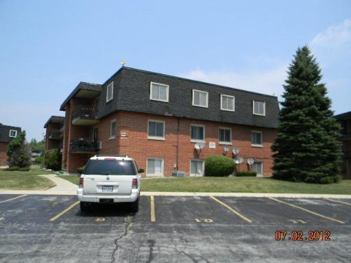 Front view of a brick apartment building with a flat roof and balconies.